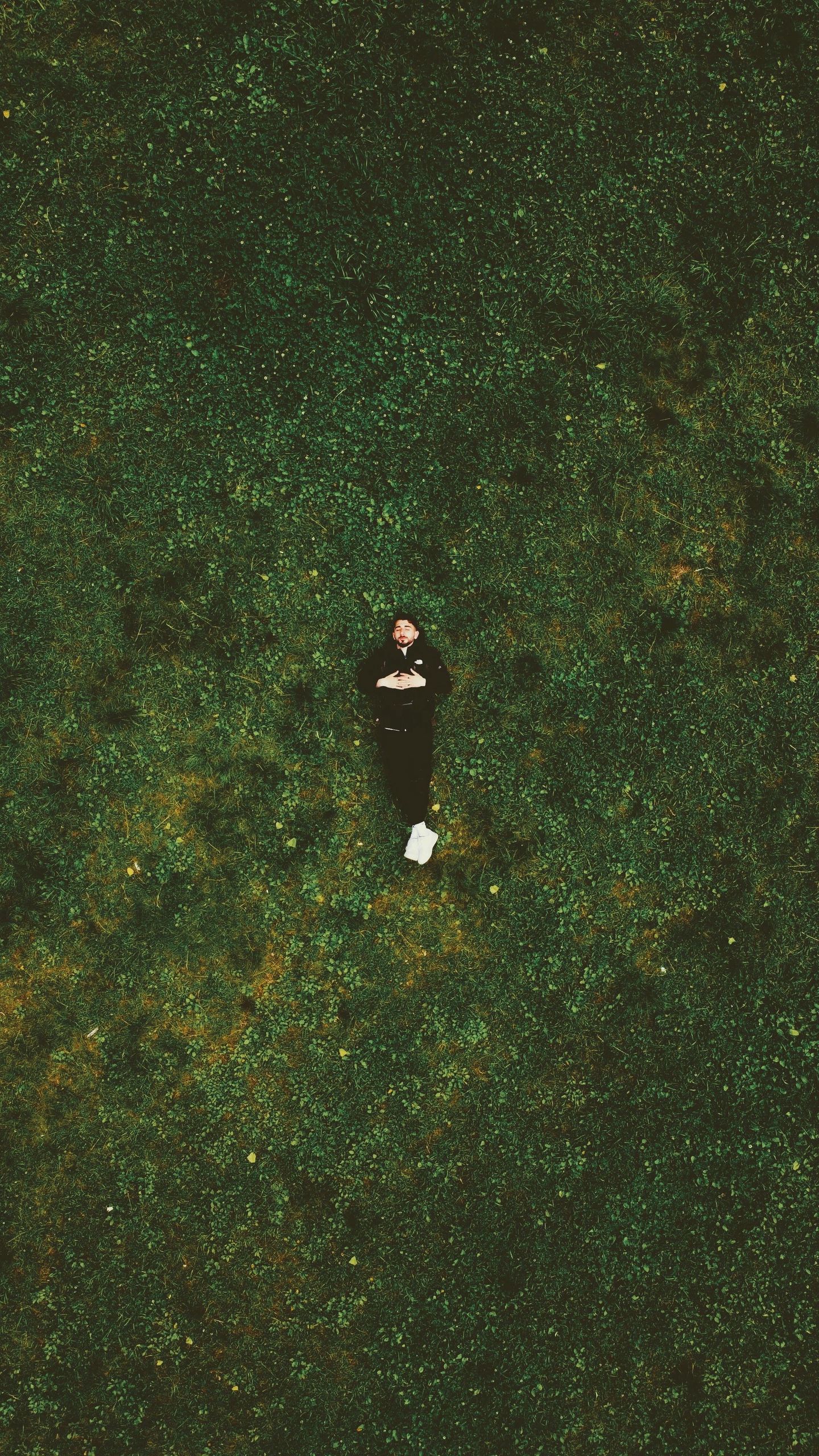 Top-down view of a person relaxing on a lush green lawn in Paris, France.